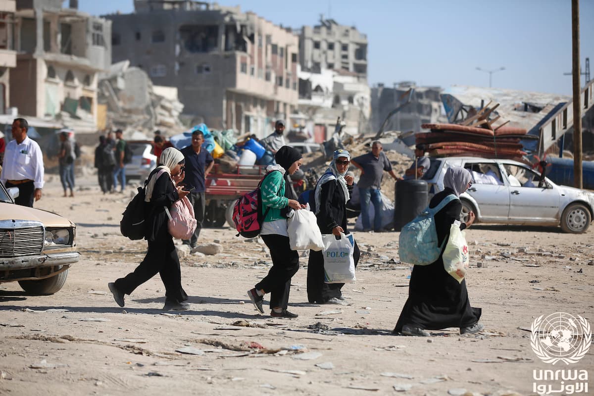 Families carry their belongings past destroyed buildings while fleeing Khan Younis, Gaza